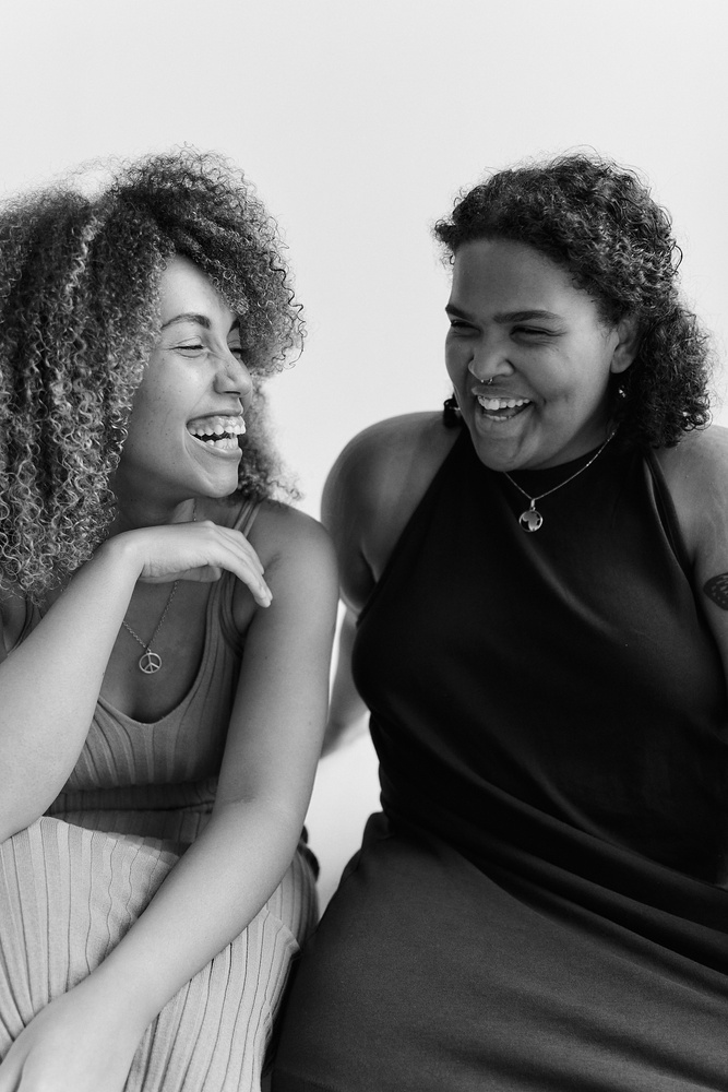 Grayscale Photo of Two Women Laughing Together